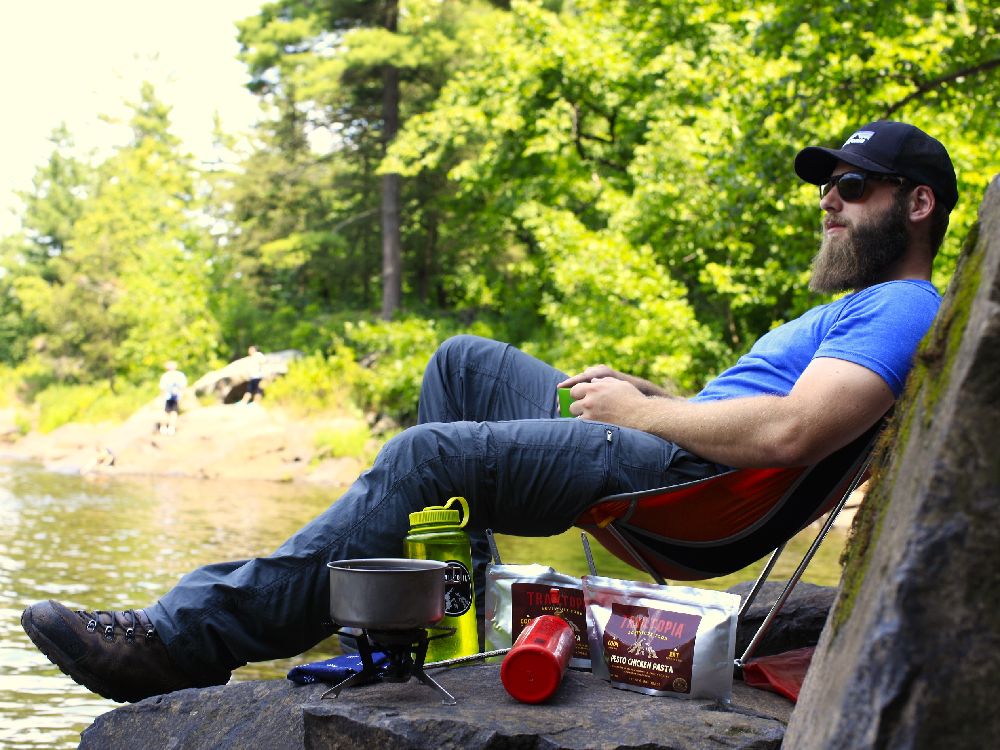Man Enjoying Sitting Near Lake as Food Cooks - Trail Food Mistakes - Trailtopia